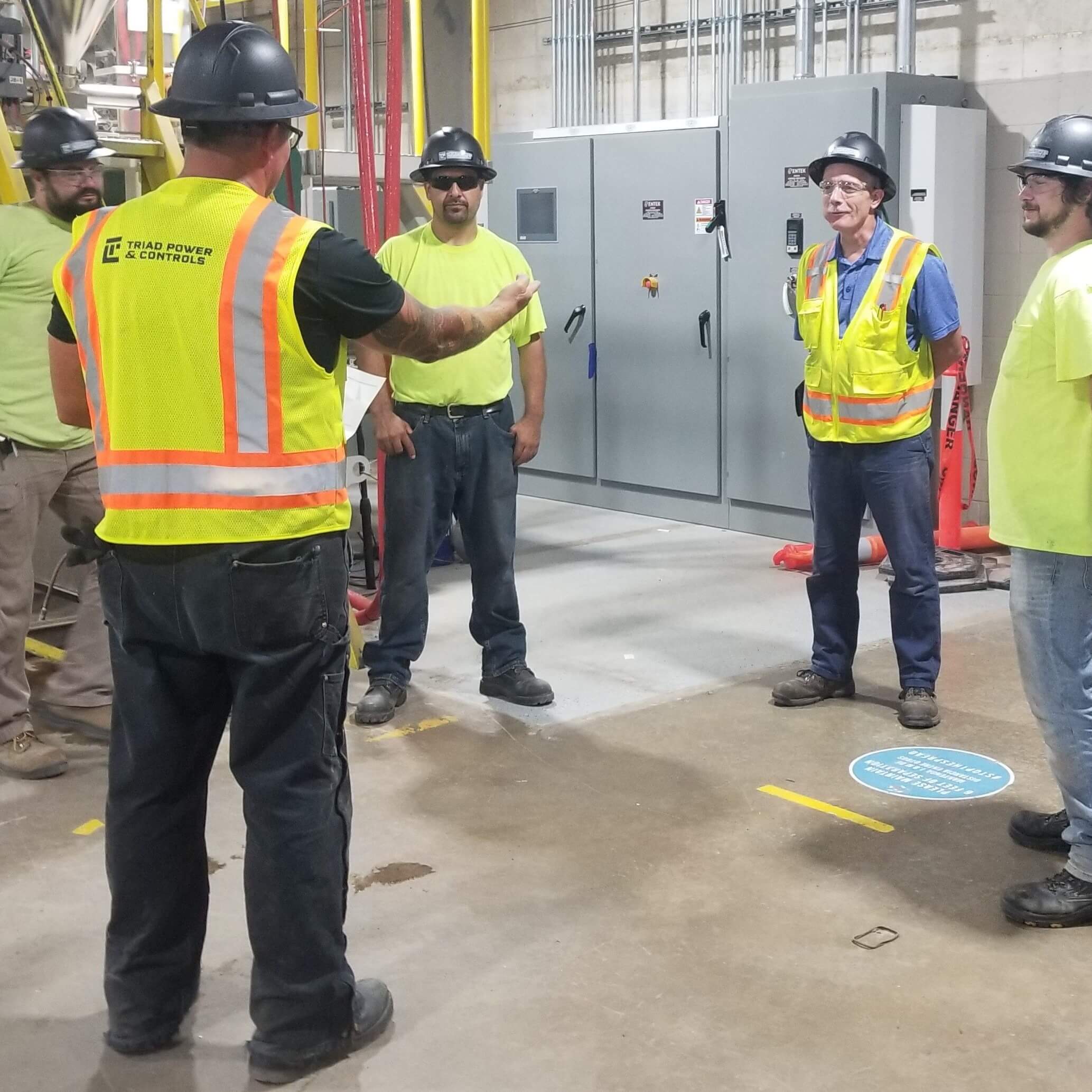 An industrial electrical control contractor discussing with people.